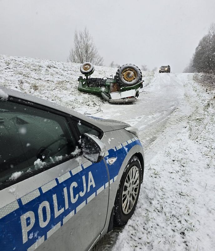 Ciągnik z zaczepioną przyczepą z drewnem wpadł w poślizg na oblodzonej drodze. W efekcie tego maszyna dachowała. Fot. KPP Staszów